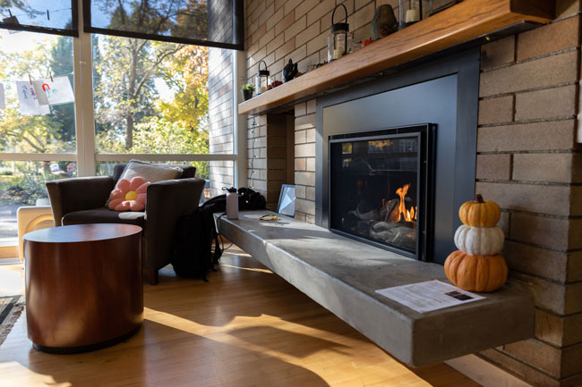 lit fireplace with a cushioned armchair and fall decorations